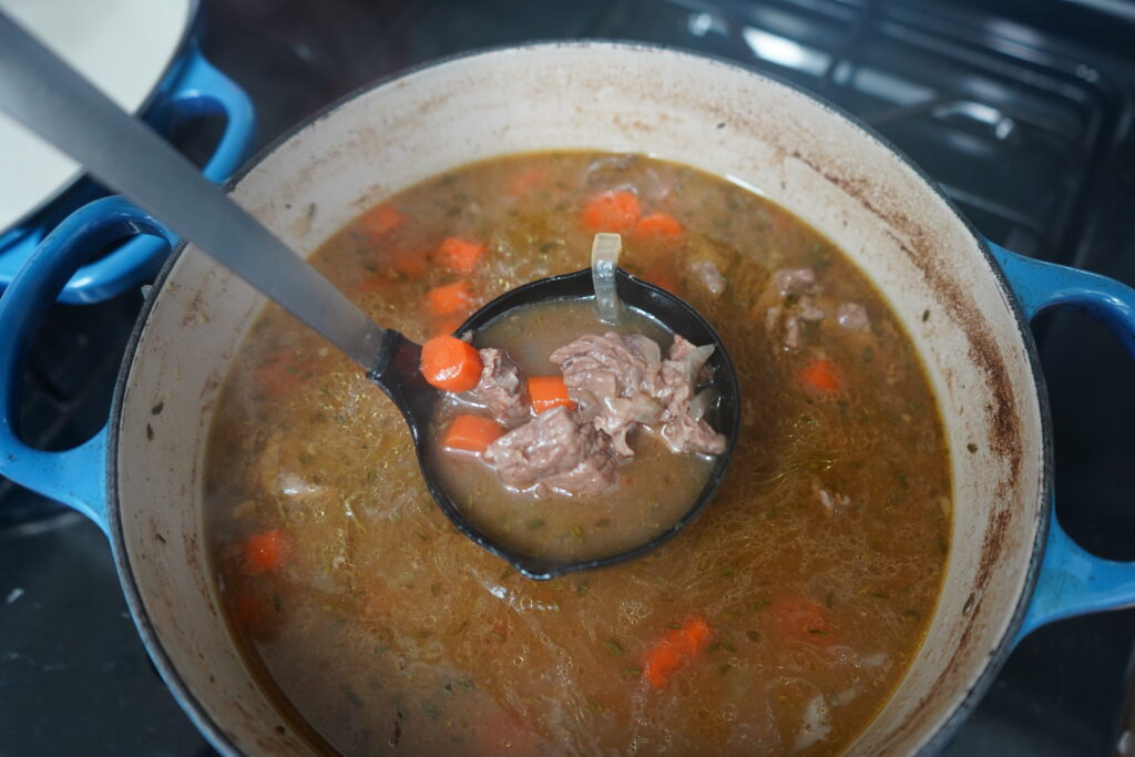 a laddle, laddling out stew from a dutch oven