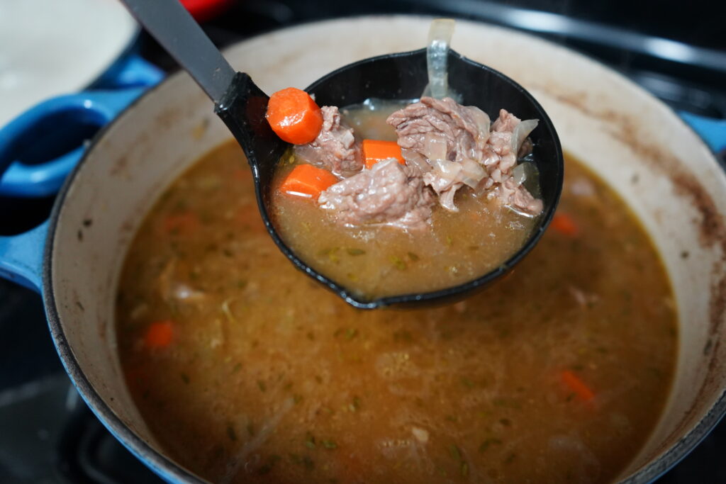 beef and carrot french stew being laddled out of a pot