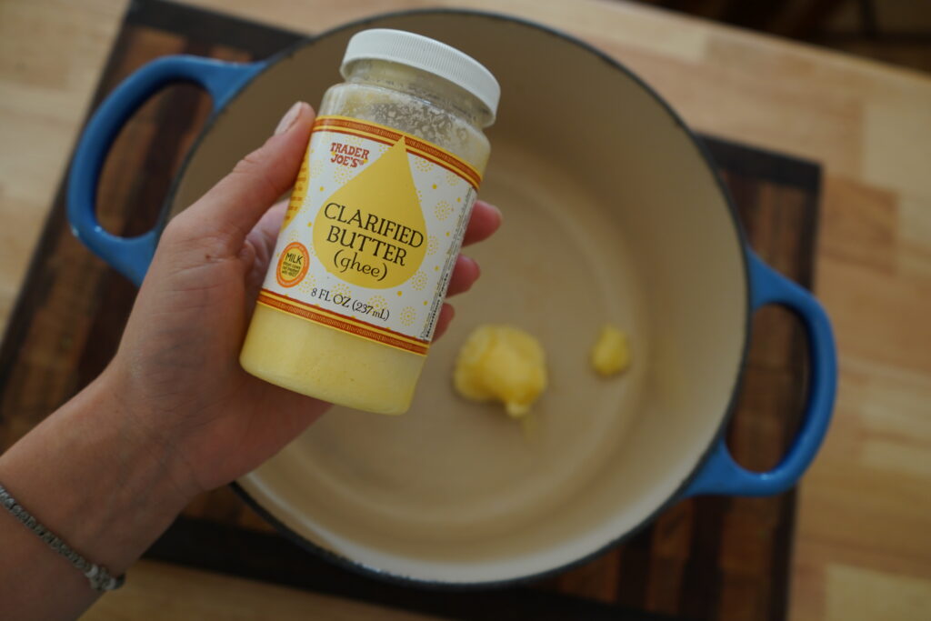 a containter of ghee over a dutch oven 