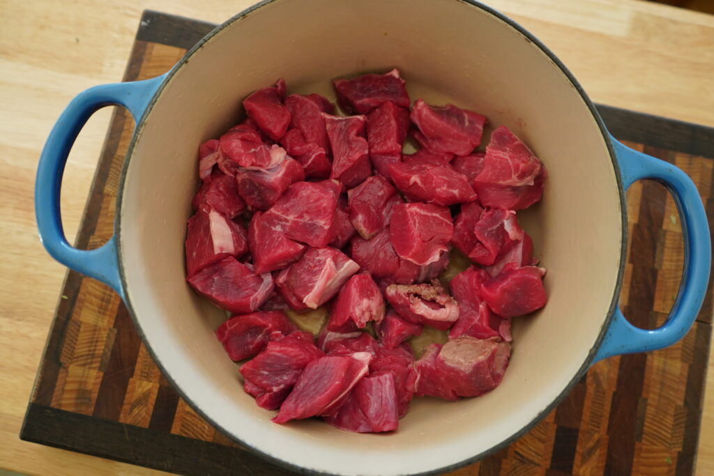 beef chunks in a blue dutch oven