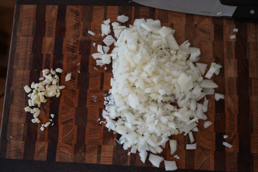 a cutting board with chopped onion and chopped garlic on it