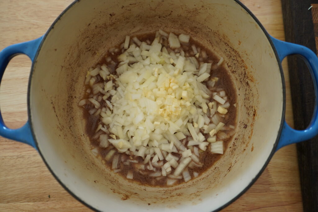 a Dutch oven with chopped onion and garlic inside