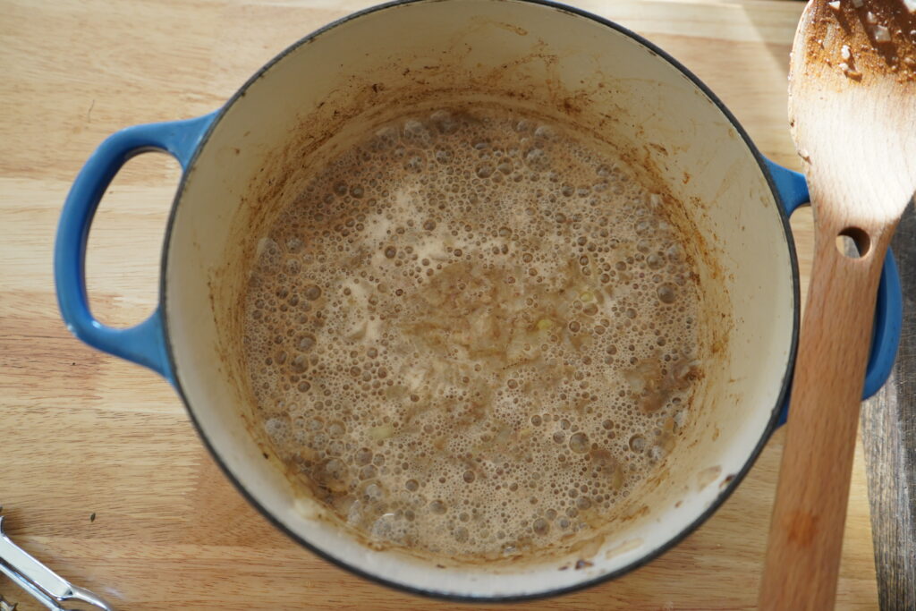 a dutch oven full of onions and beer simmering