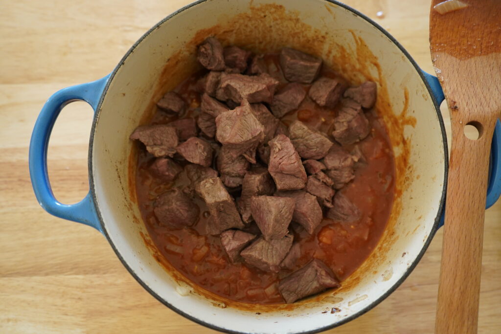 cooked beef chunks added to a dutch oven