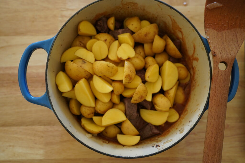 potatoes being added to the dutch oven pot