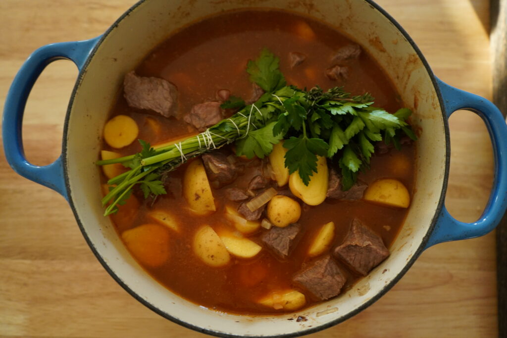 a bouquet Garni on top of the beef and potatoes in a pot