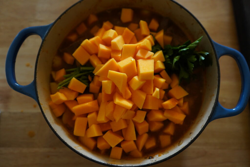 butternut squash added to a soup pot