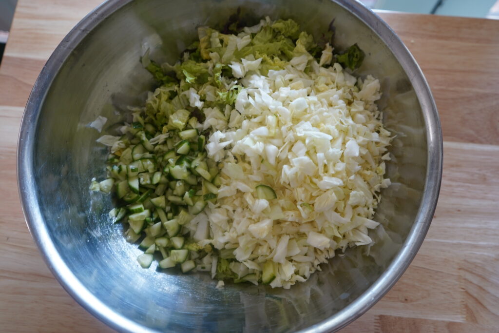 cucumber, cabbage and romaine in a mixing bowl