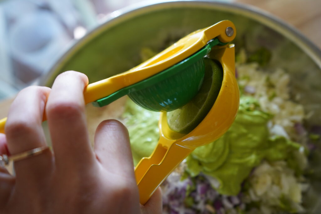 a citrus juicer juicing a lime on top on a salad