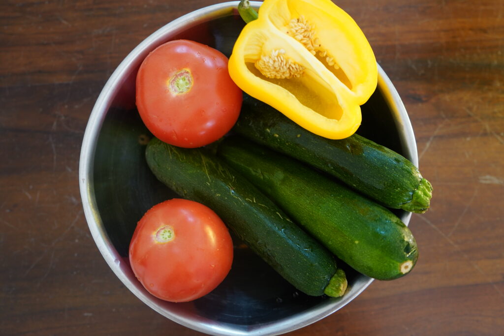 tomatoes, zucchinis and a bell pepper in a bowl