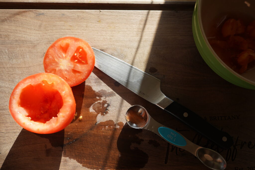 a tomato on a cutting board that has been cored