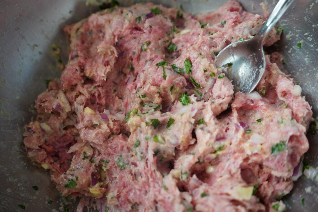 a meat mixture in a bowl with a spoon in it