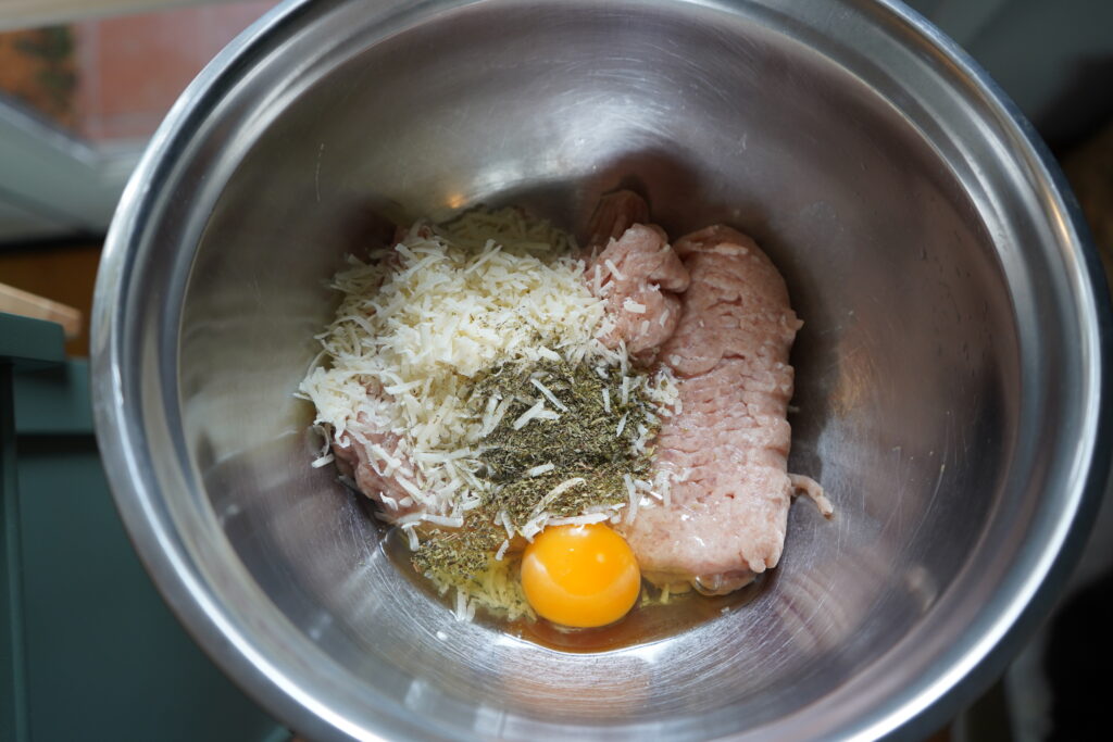 ground chicken, parmesan, an egg and seasoning in a bowl