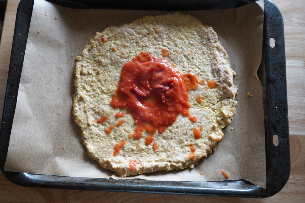 chicken pizza dough with a blop of red sauce on top