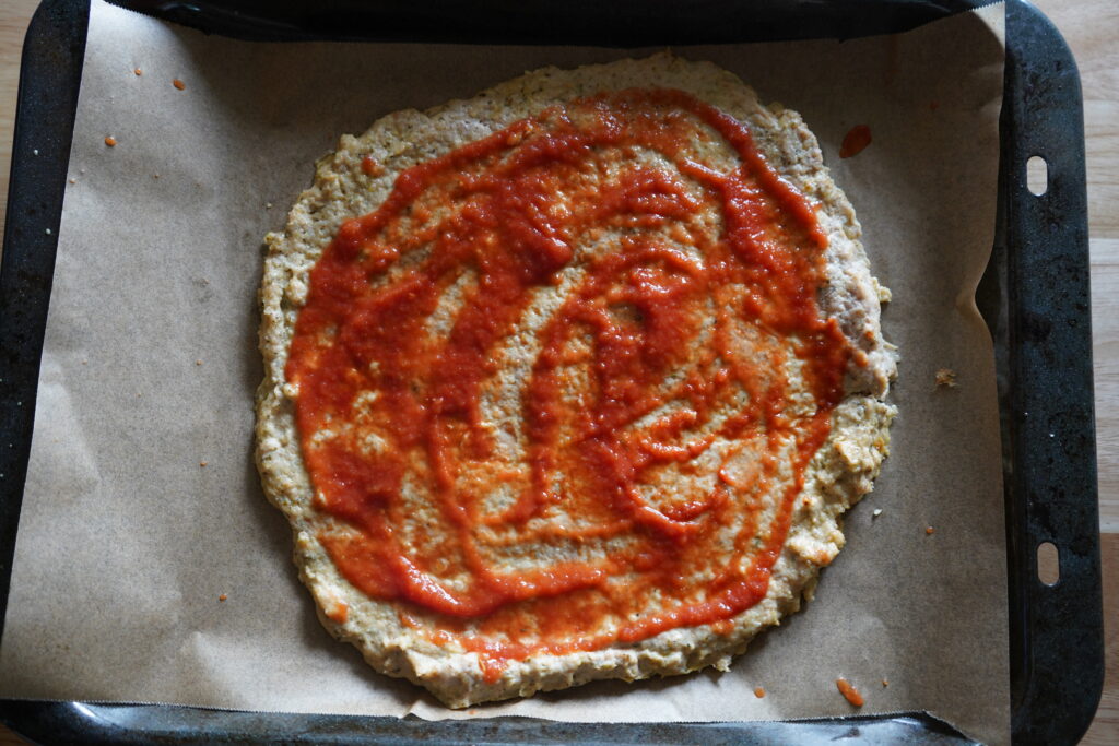 chicken pizza dough with pizza sauce spread all over it