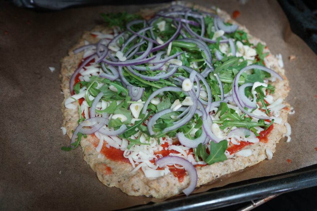 a pizza topped with onion, arugula and garlic