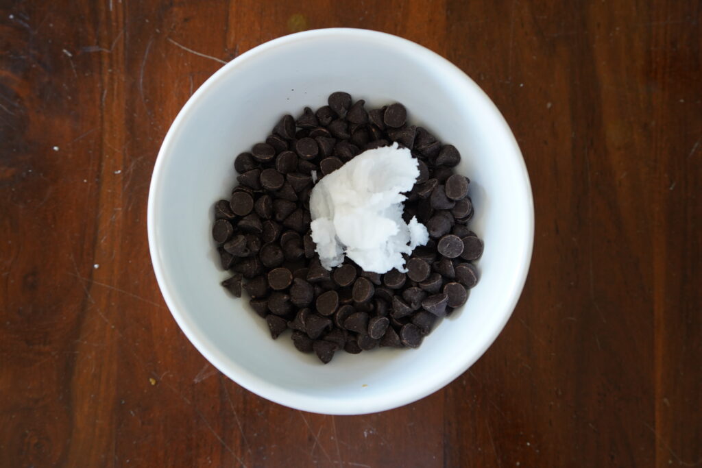 a bowl on a table with chocolate and coconut oil in a bowl