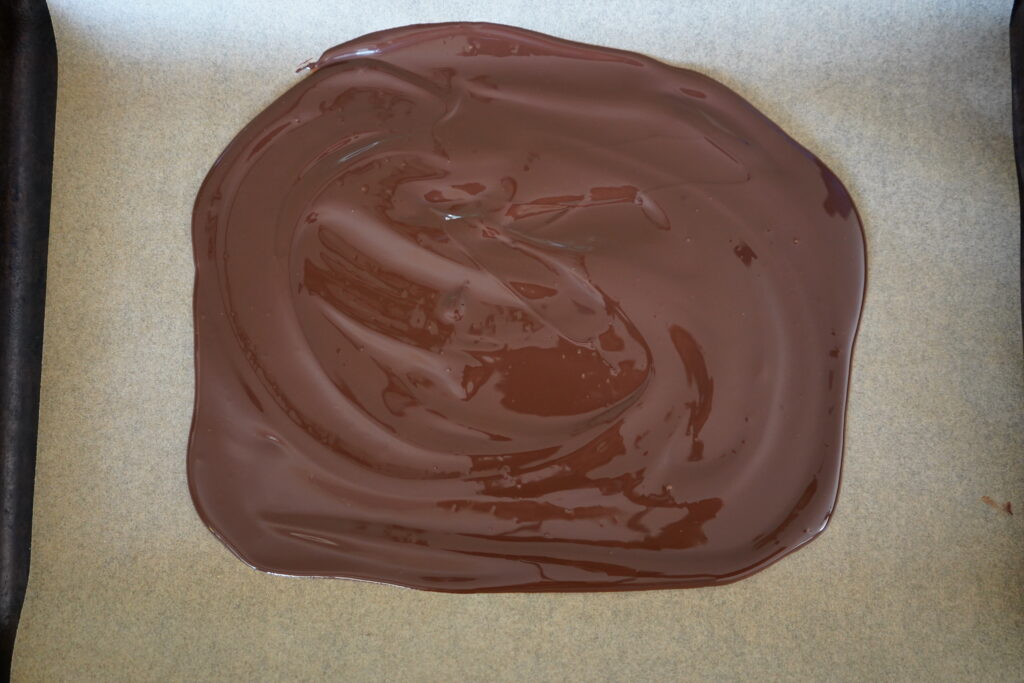 melted chocolate spread out on a parchment lined pan