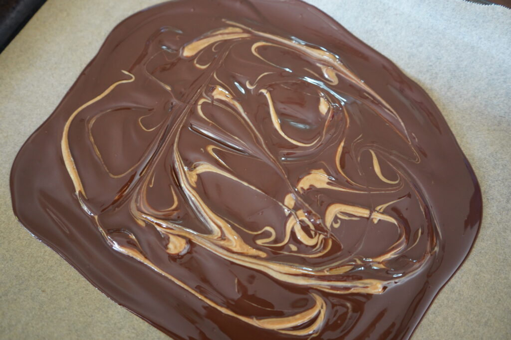 melted chocolate on parchment paper with peanut putter switrled in