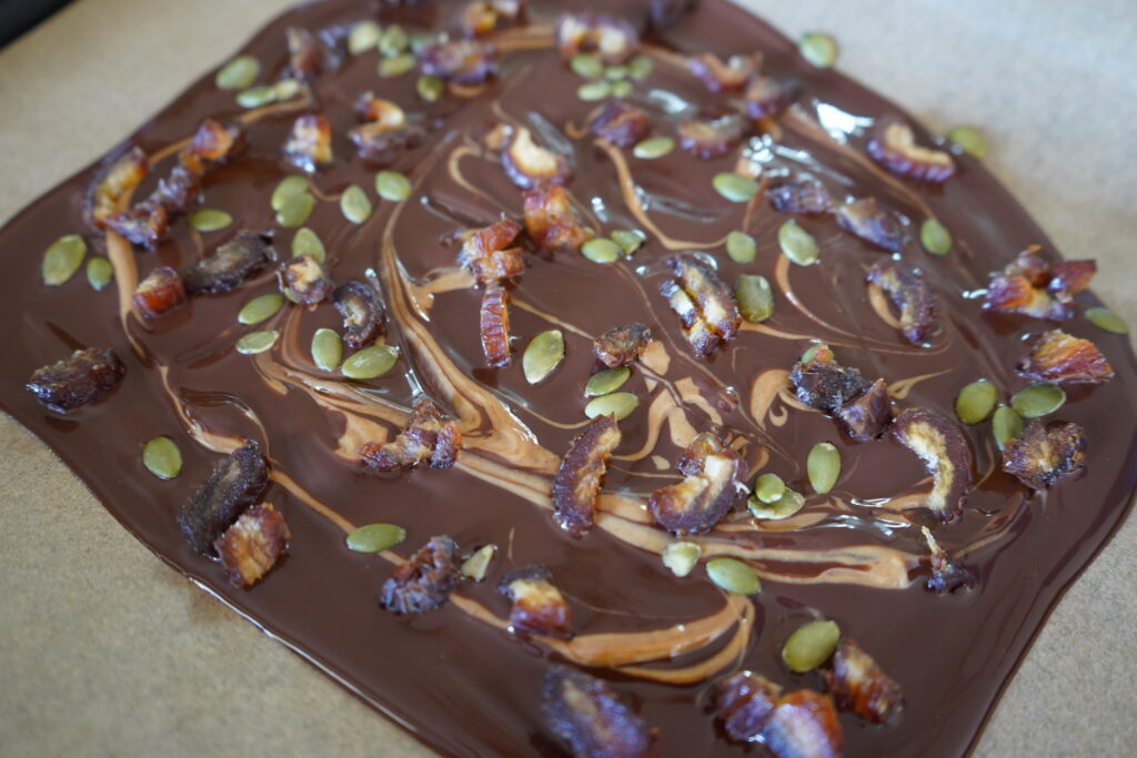 dates, pumpkin seeds, peanut butter on melted chocolate