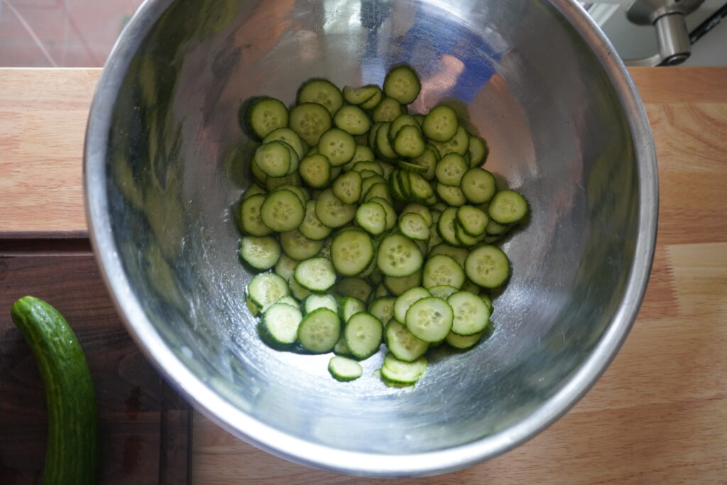 thinly slice cucumbers in a bowl