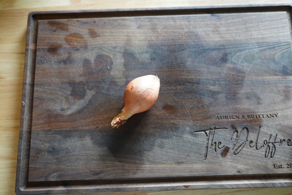 a single shallot on a wood cutting board