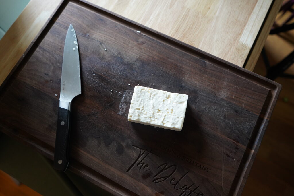 a chunk of feta on a wood cutting board