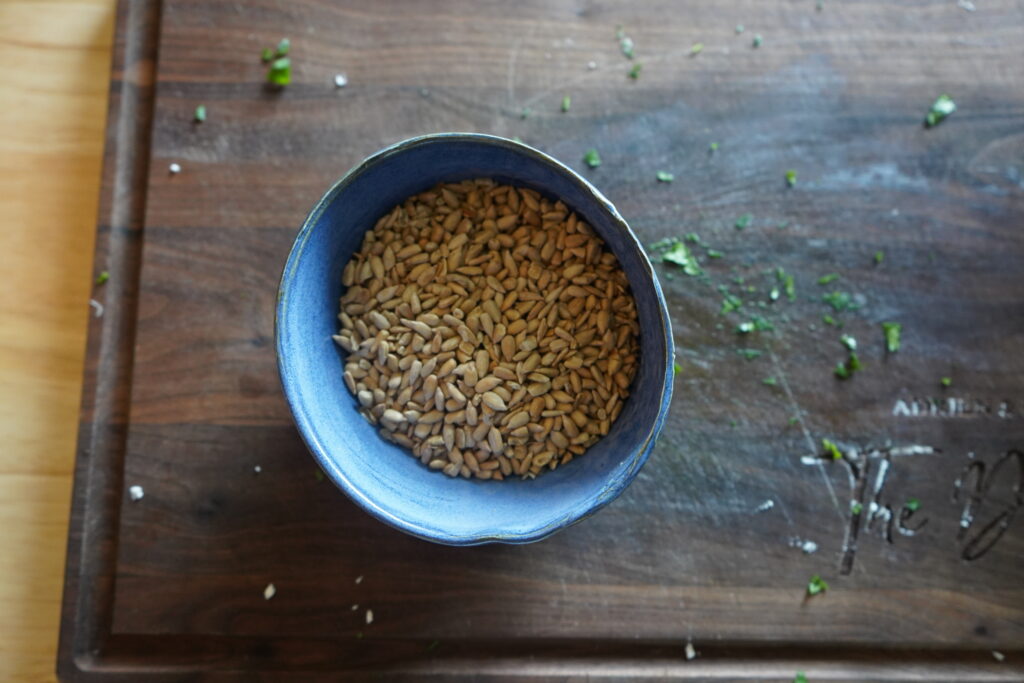 a blue ceramic bowl full of toasted sunflower seeds