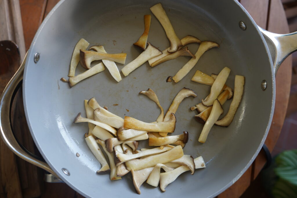 Oyster mushrooms sliced and in a pan cooking