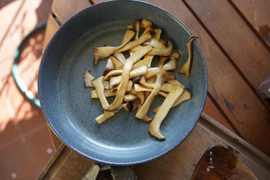 cooked, sliced oyster mushrooms in a blue bowl