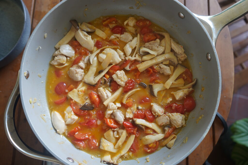 chicken, mushrooms and tomatoes cooking in a sauce
