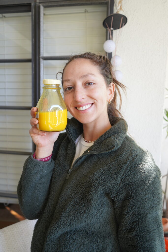 brittany holding a glass bottle of wellness shots