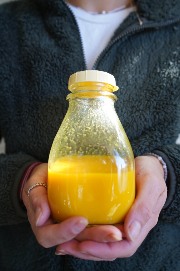 wellness shot in a glass bottle with hands holding it
