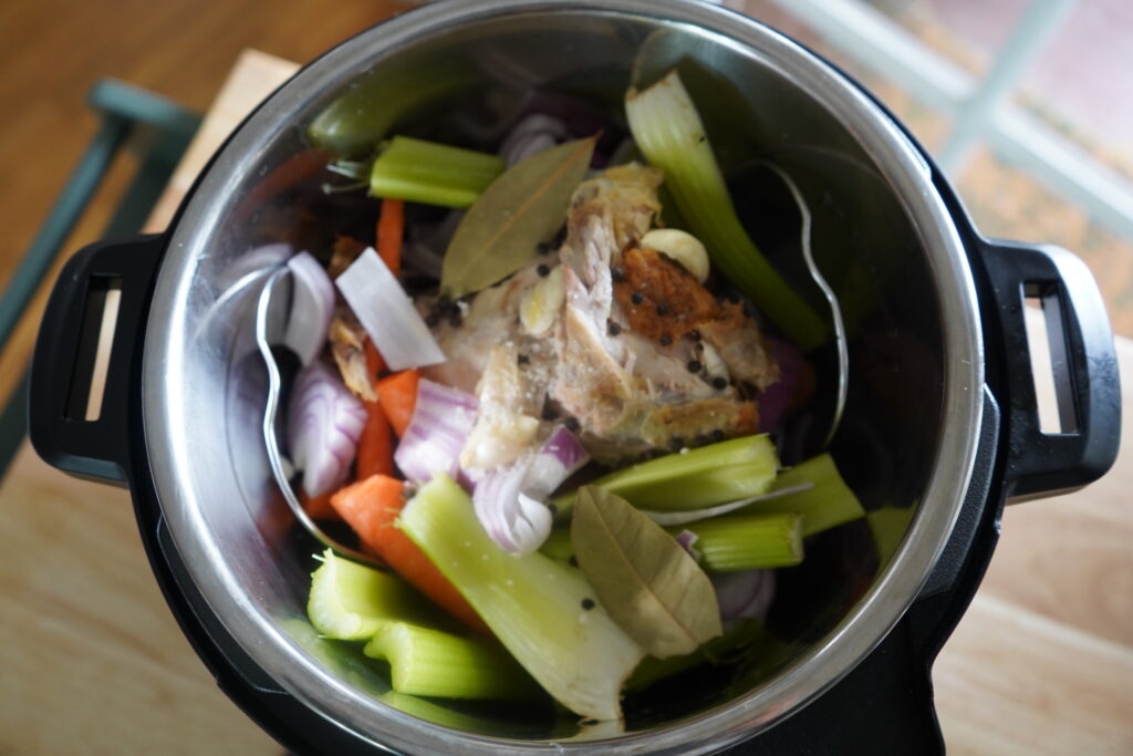 bay leaves added to an instant pot with bones and vegetables in it