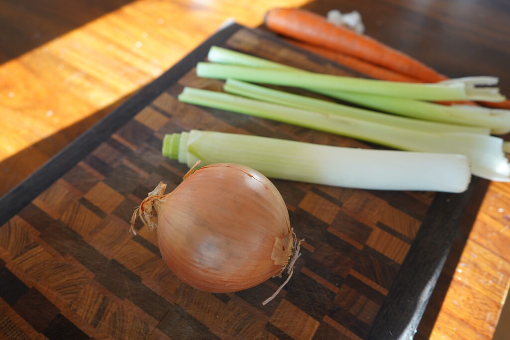 onion, leek, celery and carrot on a cutting board