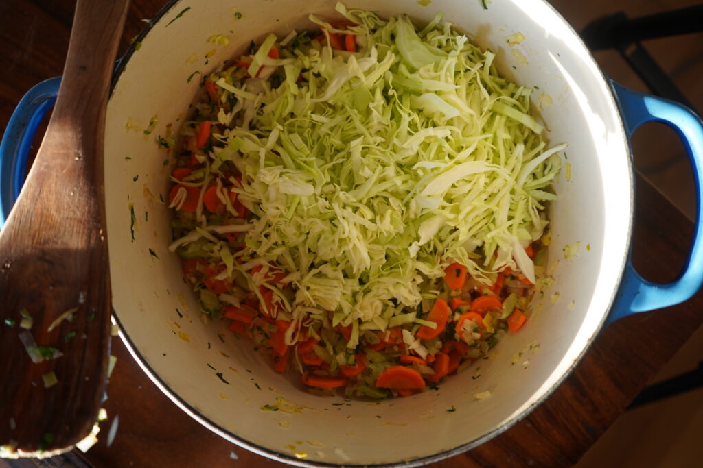 shredded cabbage added to a soup pot