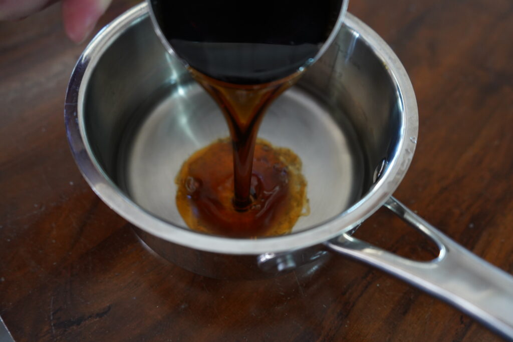 a sauce pan with water and maple syrup being poured into it