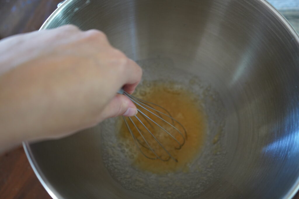 a hand whisking water and gelatin together in a mixing bowl