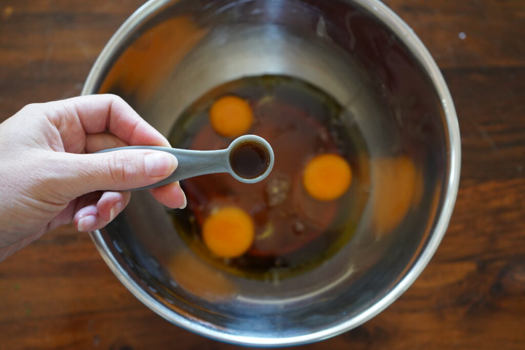 vanilla extract ebing poured into a mixing bowl of eggs 