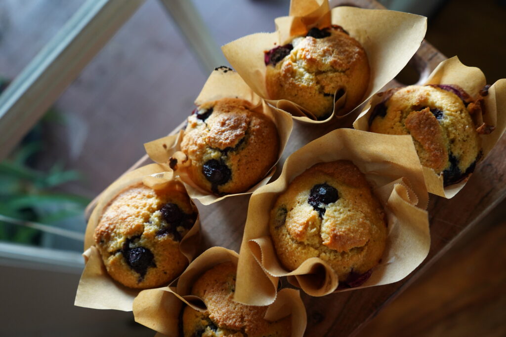 muffins next to a window with blueberries inside