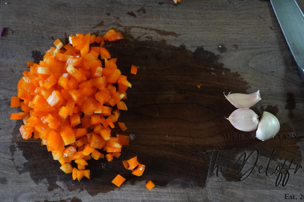 chopped bell pepper and 3 cloves of garlic on a cutting board