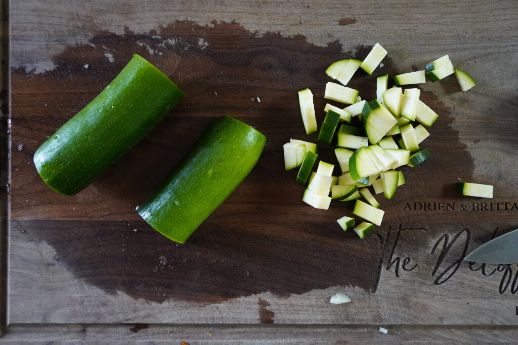zucchini being chopped on a cutting board