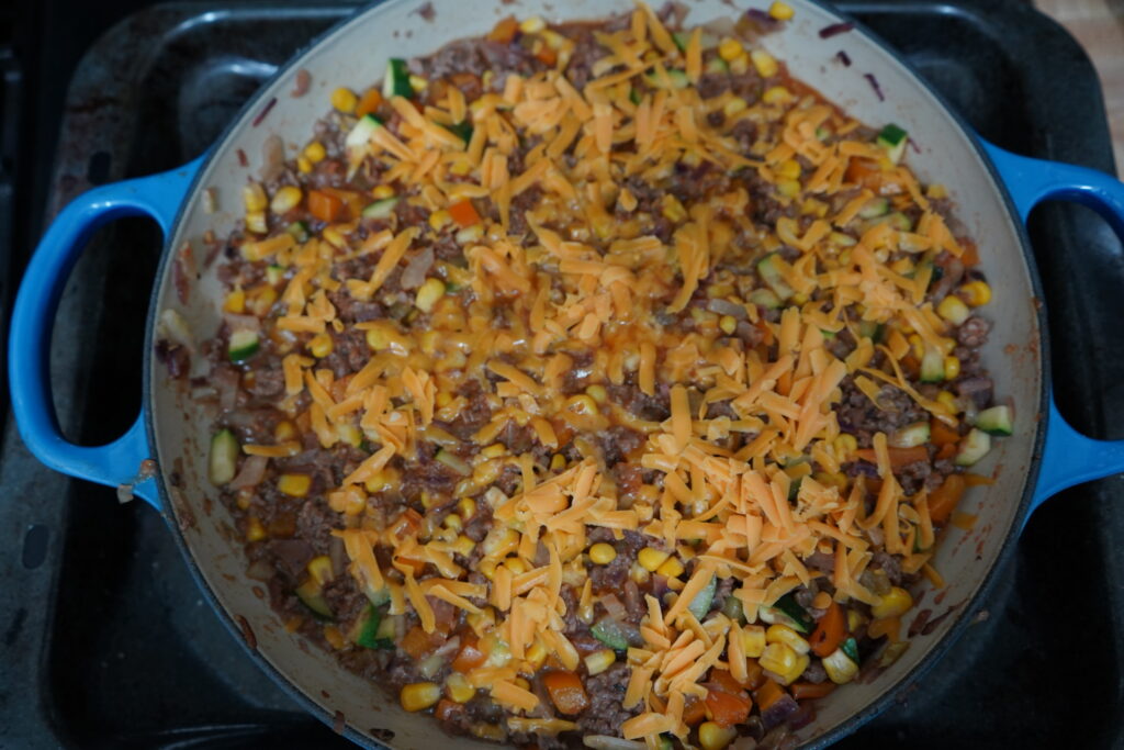 cheese sprinkled on top of a enchilada skillet