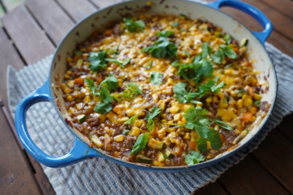 a skillet of enchilada topped with cheese and cilantro