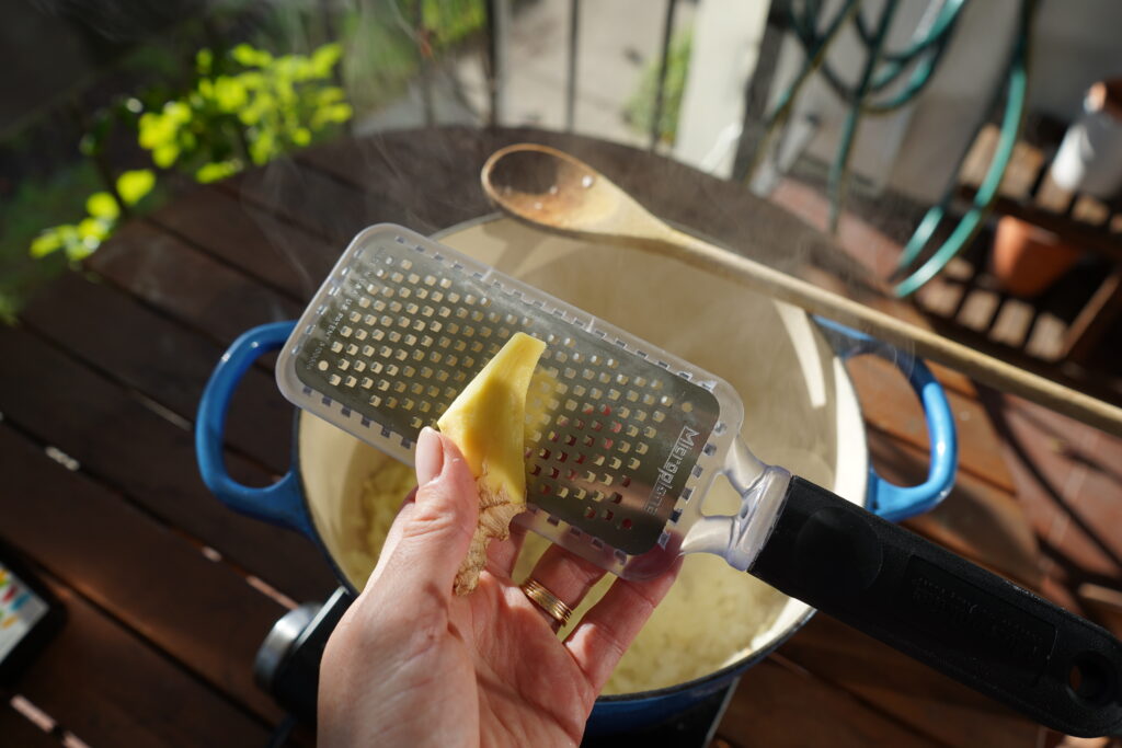 ginger being zested into a pot of 