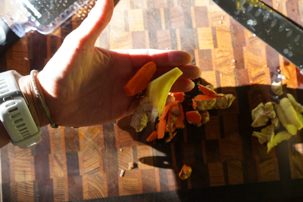 a hand holding peeled ginger and turmeric