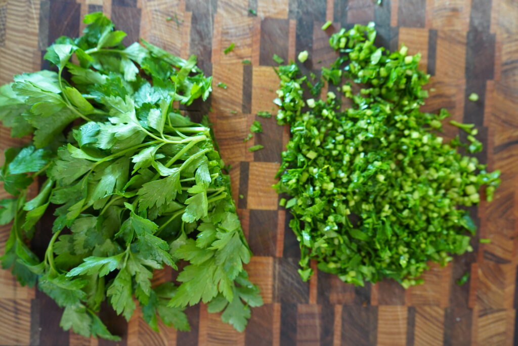 parsley stems being chopped on a cutting board
