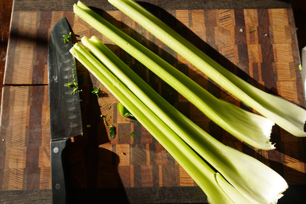 celery on a cutting board next to aknife about to be chopped