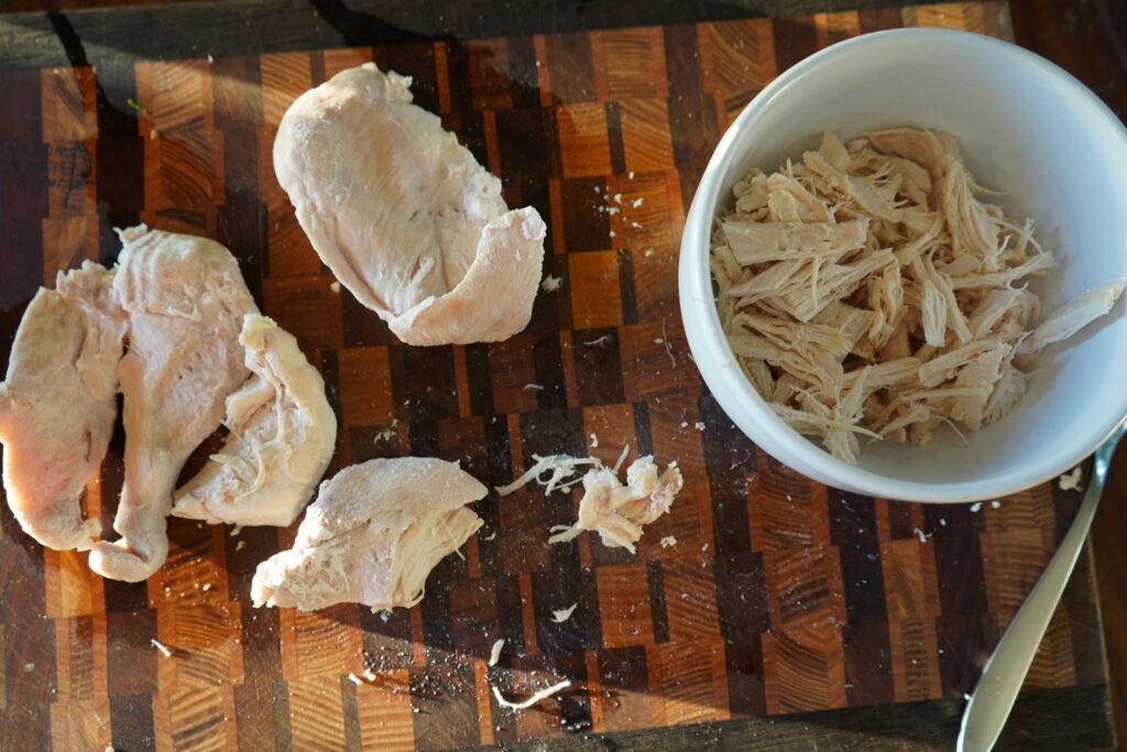 chicken being shredded on a cutting board
